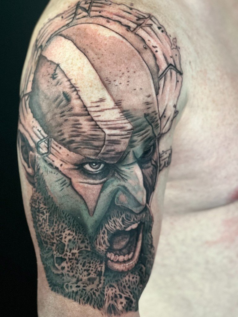 Illustrative realism tattoo of Kratos roaring, on an upper arm
