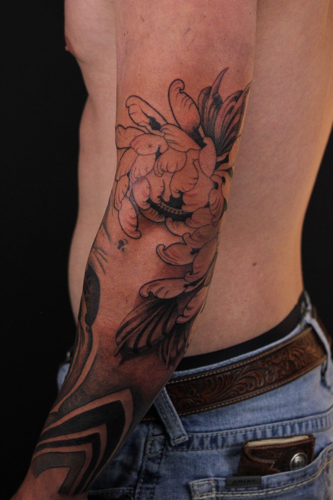 Black and grey chrysanthemum tattoo with geometric neo-tribal bands on an outer arm